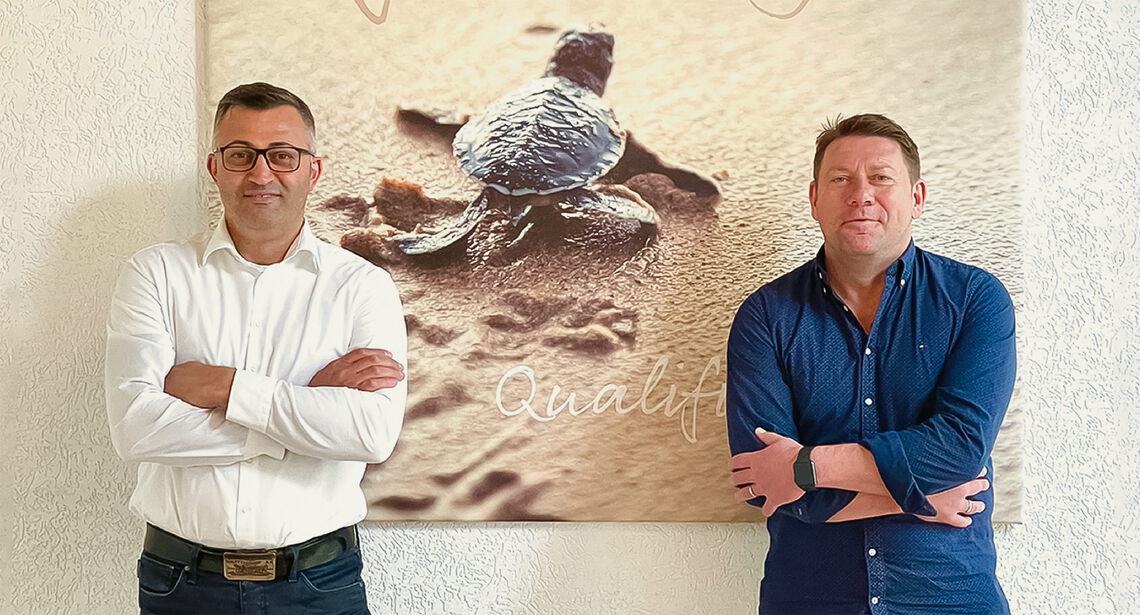 Zwei Männer stehen vor einem Bild mit Schildkröte, das symbolisch für die Betreuung in einer Außerklinischen Wohngemeinschaft ist.